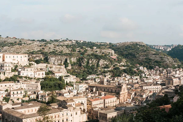 Sunlight on small houses near green trees against sky with clouds in ragusa, italy — Stock Photo