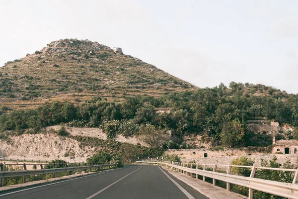 Estrada de asfalto perto de árvores verdes na colina em ragusa, itália — Fotografia de Stock