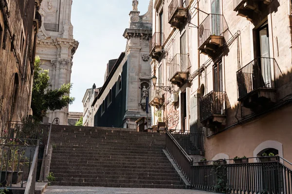 CATANIE, ITALIE - 3 OCTOBRE 2019 : vue en angle bas de la façade de la cathédrale de Catane près des escaliers et des maisons avec balcons — Photo de stock