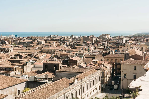 Lumière du soleil sur les toits bruns de vieilles maisons près de la mer à Catane, en Italie — Photo de stock