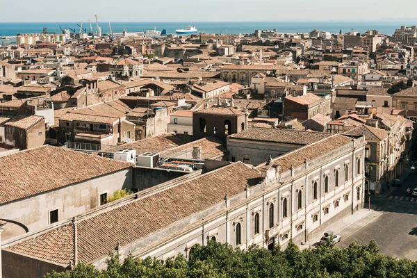 Luz del sol en los tejados de casas antiguas cerca del mar azul en Catania, Italia - foto de stock