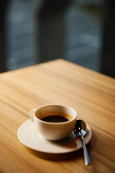 Selective focus of white cup with coffee near spoon in cafe — Stock Photo