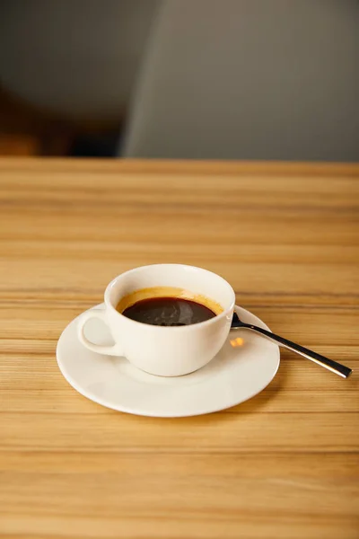 Taza blanca con café cerca de cuchara en la cafetería - foto de stock