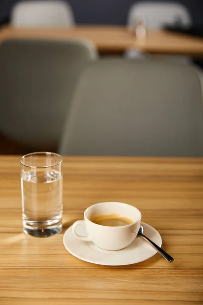 Selective focus of cup of hot coffee near glass with cold water in cafe — Stock Photo