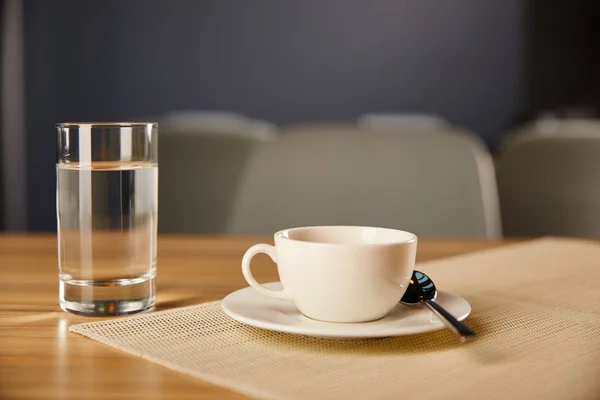 Selektiver Fokus der Tasse Kaffee in der Nähe von Glas mit Wasser im Café — Stockfoto