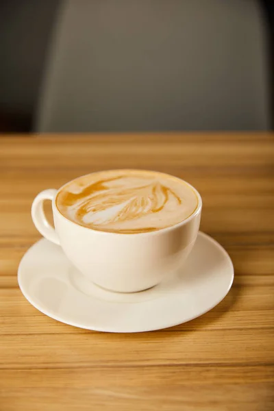 Savoureux cappuccino en tasse blanche avec soucoupe sur la table — Photo de stock