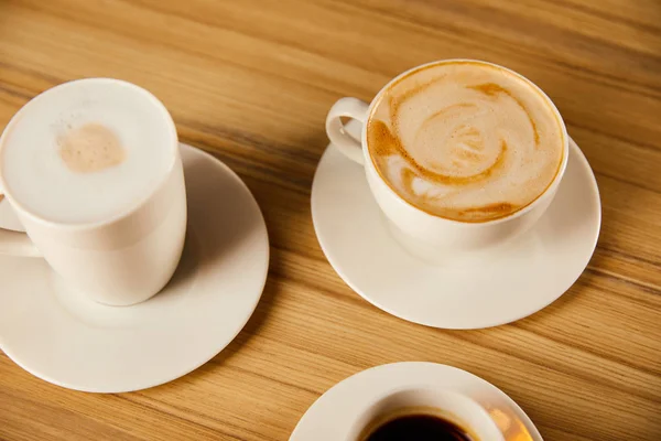 Platillos con tazas blancas de sabroso café en la cafetería - foto de stock