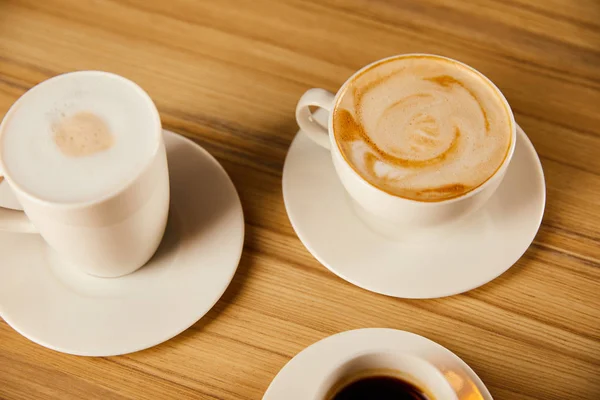 Saucers with white cups of tasty coffee in cafe — Stock Photo