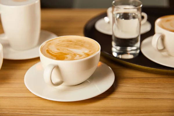 Foco seletivo de pires com xícaras de café saboroso no café — Fotografia de Stock