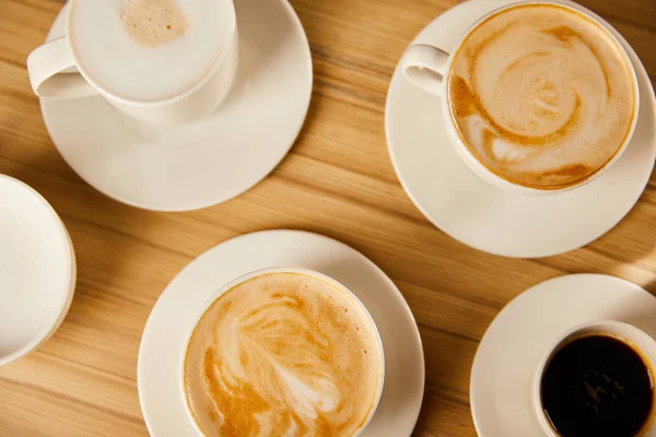 Top view of saucers with cups of different coffee — Stock Photo