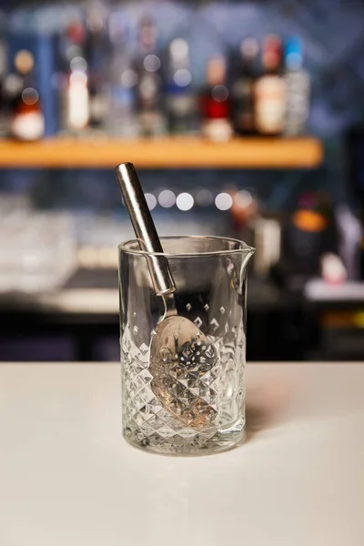 Silver spoon in empty glass on bar counter — Stock Photo
