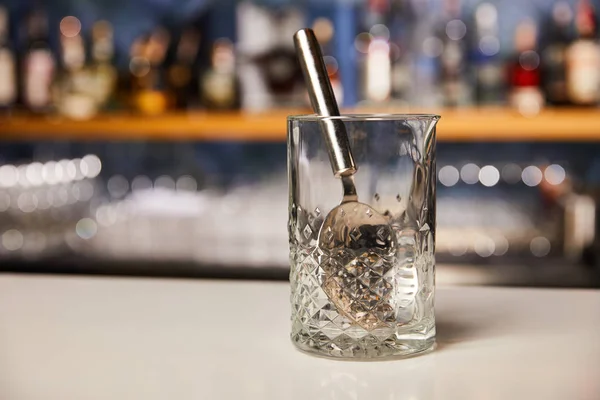 Silver spoon in empty glass on bar stand — Stock Photo