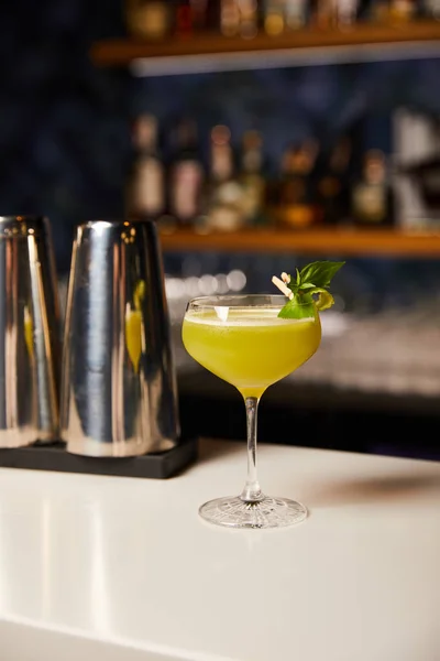 Склянка зі змішаним алкогольним коктейлем біля шейкера на барній стійці — стокове фото