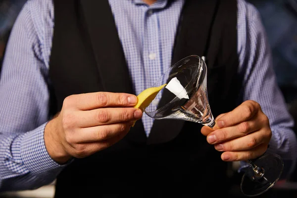 Cropped view of barman holding sliced lemon near margarita glass — Stock Photo