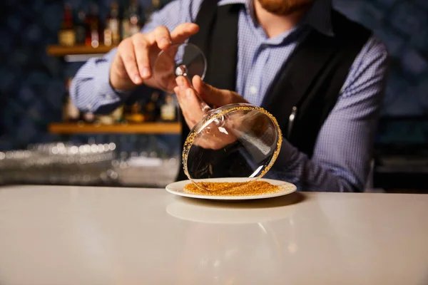 Zugeschnittene Ansicht des Barmannes, der Margaritaglas in der Nähe der Untertasse mit braunem Zucker hält — Stockfoto