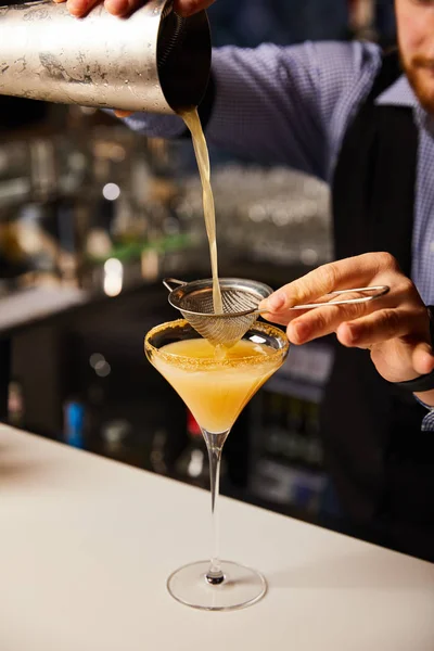 Vista cortada de barman derramando coquetel enquanto segurando agitador perto da peneira e vidro margarita — Fotografia de Stock