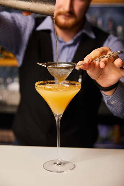 Abgeschnittene Ansicht von Barkeeper, der Cocktail einschenkt, während er Shaker in der Nähe von Sieb und Margaritenglas hält — Stockfoto