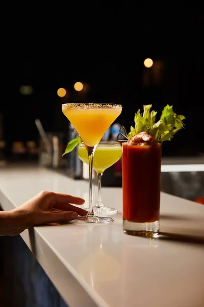 Обрезанный вид женщины, касающейся бокала Маргариты со свежим коктейлем на барной стойке — стоковое фото