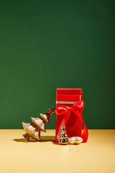 Boîte cadeau rouge et arbre de Noël décoratif avec des boules d'or sur fond vert — Photo de stock