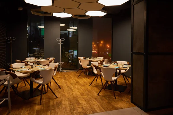Gläser neben Tellern auf Holztischen in modernem Restaurant — Stockfoto