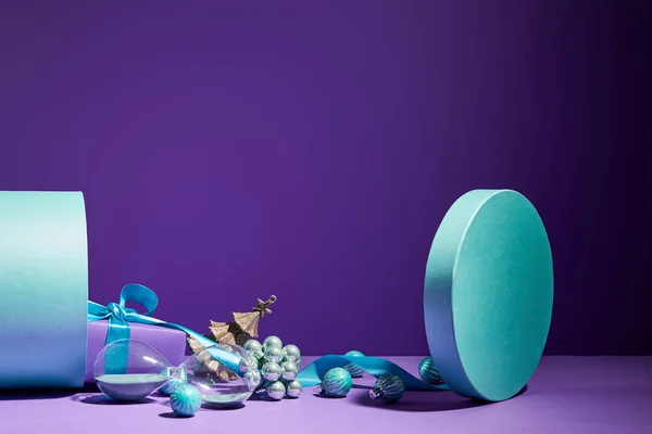 Décoration de Noël et sablier dispersés de boîte cadeau bleue sur fond violet — Photo de stock