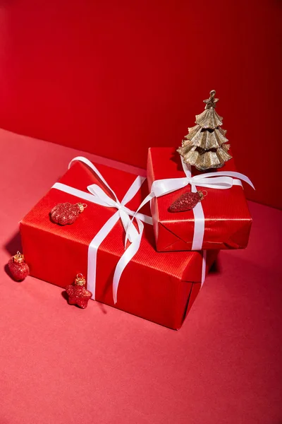 Caixas de presente vermelho e árvore de Natal dourada decorativa com bugigangas no fundo vermelho — Fotografia de Stock