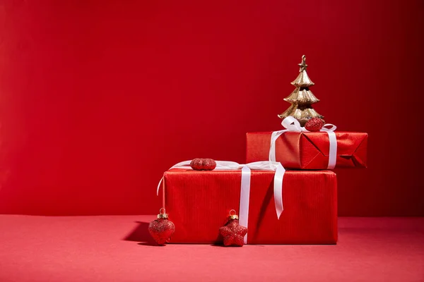 Cajas de regalo rojas y árbol de Navidad dorado decorativo con adornos sobre fondo rojo - foto de stock