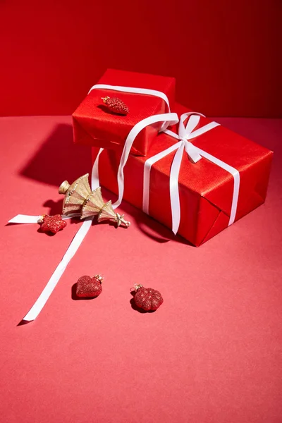 Boîtes-cadeaux rouges et arbre de Noël doré décoratif avec des boules sur fond rouge — Photo de stock