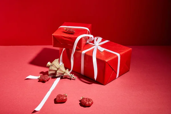 Caixas de presente vermelho e árvore de Natal dourada decorativa com bugigangas no fundo vermelho — Fotografia de Stock