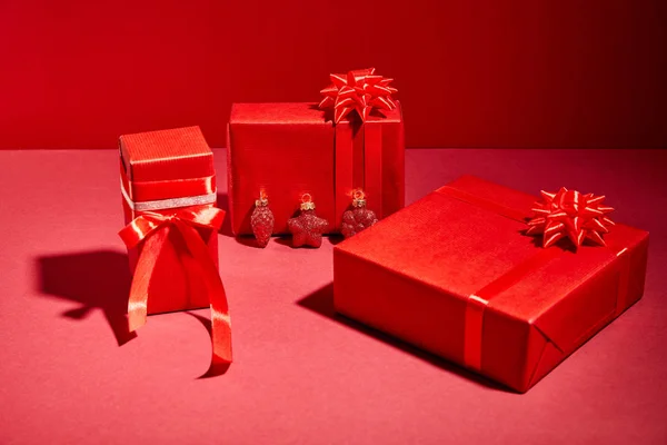 Cajas de regalo festivas envueltas en rojo con cintas y arcos sobre fondo rojo - foto de stock