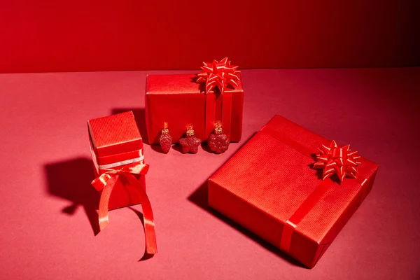 Red wrapped festive gift boxes with ribbons and bows on red background — Stock Photo