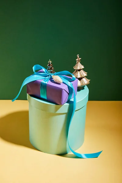 Caja de regalo con decoración de Navidad dorada sobre fondo verde y amarillo - foto de stock