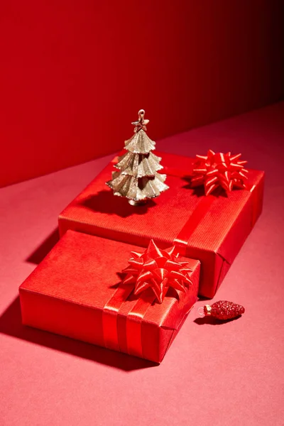 Boîtes-cadeaux rouges et arbre de Noël doré décoratif sur fond rouge — Photo de stock