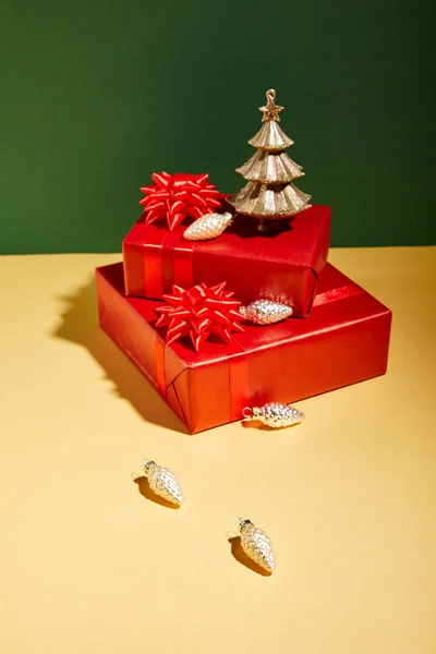 Red gift boxes and golden Christmas decor on yellow and green background — Stock Photo