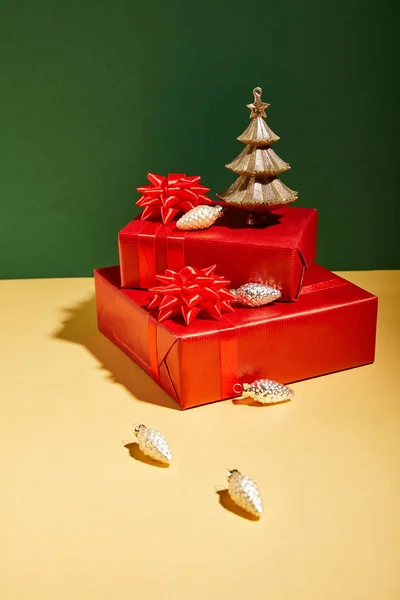 Rote Geschenkboxen und goldenes Weihnachtsdekor auf gelbem und grünem Hintergrund — Stockfoto