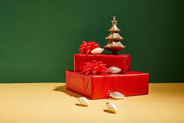 Red gift boxes and golden Christmas decor on yellow and green background — Stock Photo