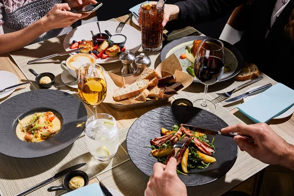 Vista cortada de pessoas comendo comida deliciosa no restaurante — Fotografia de Stock