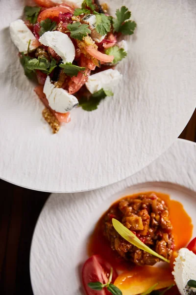 Vista superior de delicioso prato de restaurante com caviar de berinjela e tomates e salada em mesa de madeira — Fotografia de Stock