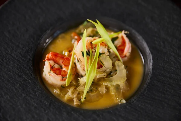 Nahaufnahme von köstlicher Restaurantsuppe mit Garnelen in schwarzem Teller — Stockfoto