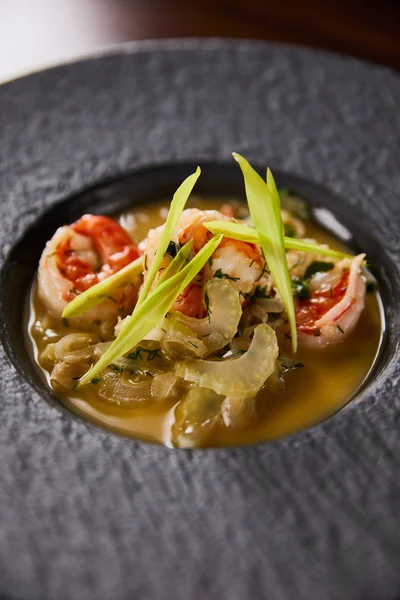 Close up view of delicious restaurant soup with shrimps in black plate — Stock Photo