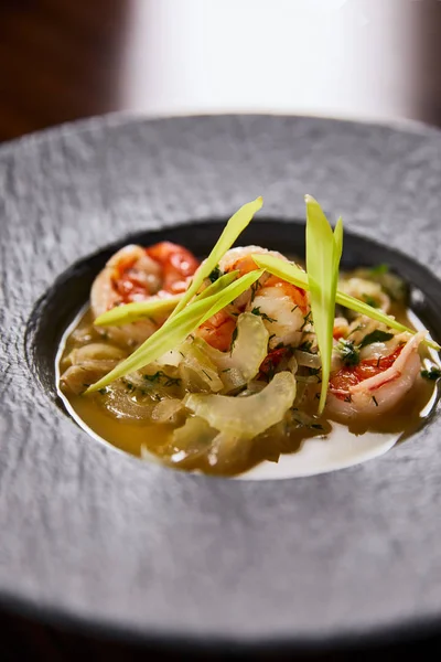 Close up view of delicious restaurant soup with shrimps in black plate — Stock Photo