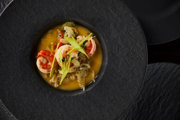 Blick von oben auf köstliche Restaurantsuppe mit Garnelen in schwarzem Teller — Stockfoto