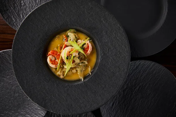 Blick von oben auf köstliche Restaurantsuppe mit Garnelen in schwarzem Teller — Stockfoto