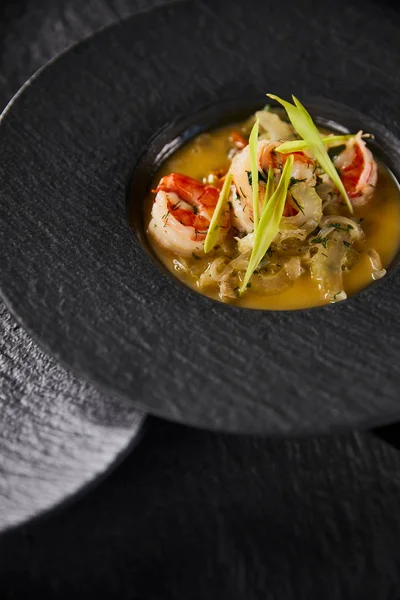 Köstliche Restaurantsuppe mit Garnelen im schwarzen Teller — Stockfoto