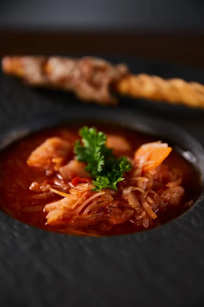 Vista de cerca del borscht tradicional ucraniano adornado con perejil en plato negro - foto de stock