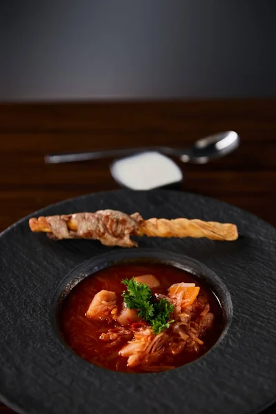 Traditional ukrainian borscht garnished with parsley in black plate — Stock Photo