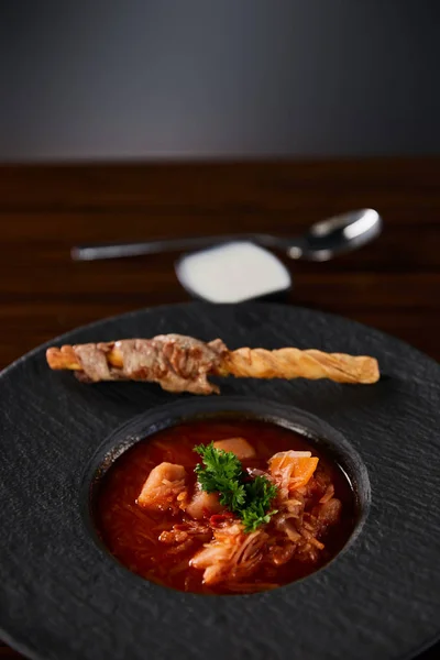 Borscht tradicional ucraniano adornado con perejil en plato negro - foto de stock