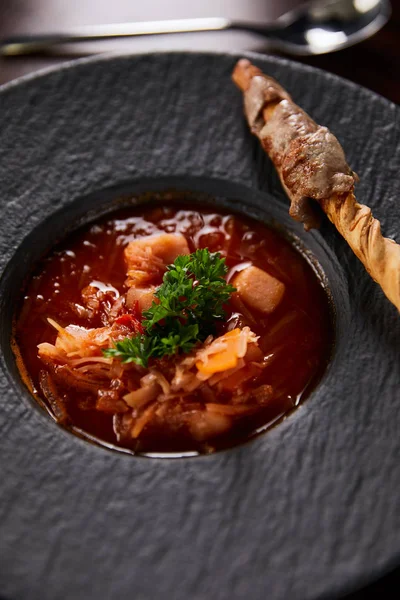 Borscht tradicional ucraniano adornado con perejil en plato negro - foto de stock