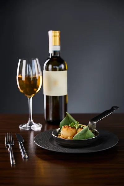 Deliciosas vieiras a la parrilla servidas con cubiertos y vino blanco sobre mesa de madera - foto de stock