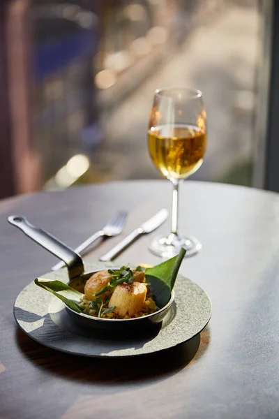 Selective focus of delicious grilled scallops served in pan with microgreens near white wine in sunlight — Stock Photo